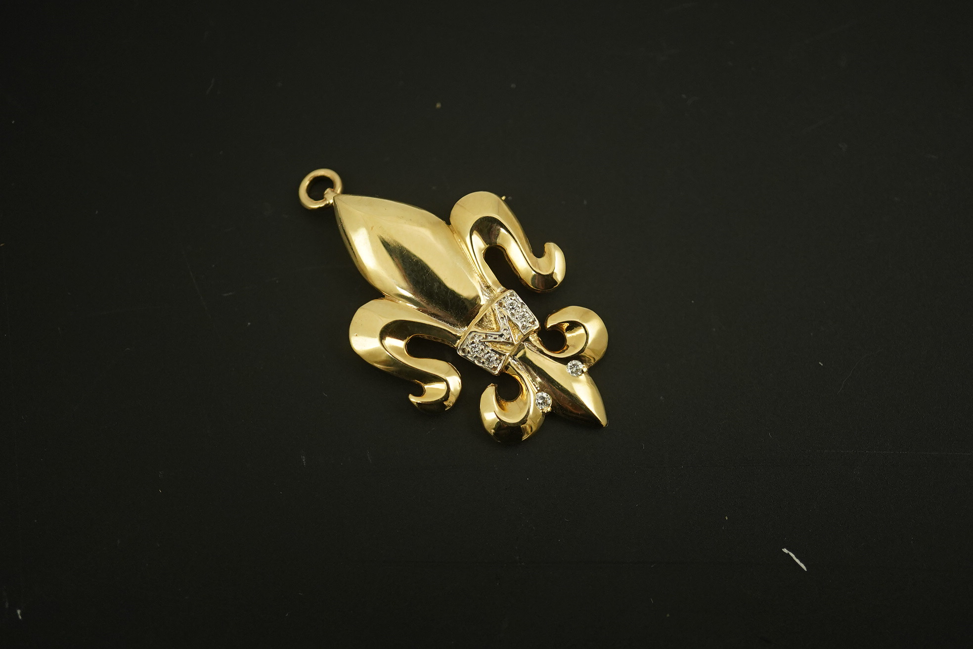 A modern 14k gold and diamond chip cluster set fleur de lys pendant